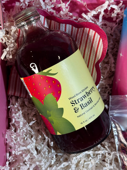 Bottle of strawberry and basil-flavored syrup with a label on a textured surface.